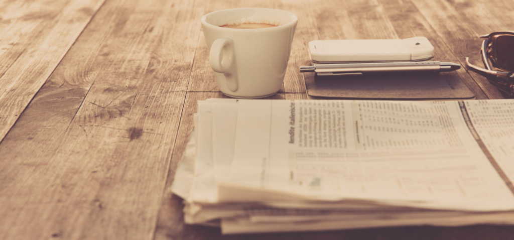 Journal avec la veille de l'AFF et café sur une table.