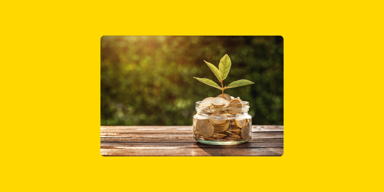 Bocal rempli de pièces de monnaie, posé sur un banc dans la nature, avec une jeune pousse verte à l'intérieur qui symbolise la croissance financière et l'investissement solidaire.