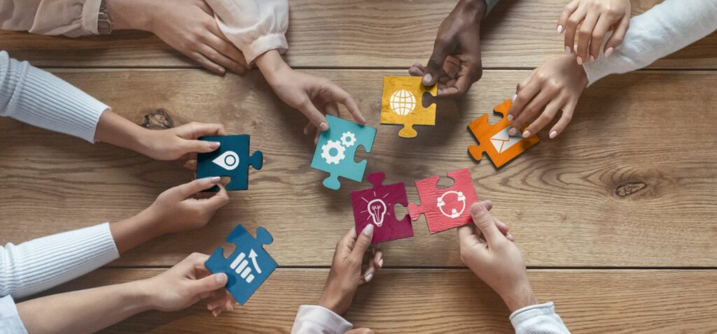 Plusieurs mains tenant chacune une grosse pièce de puzzle différente