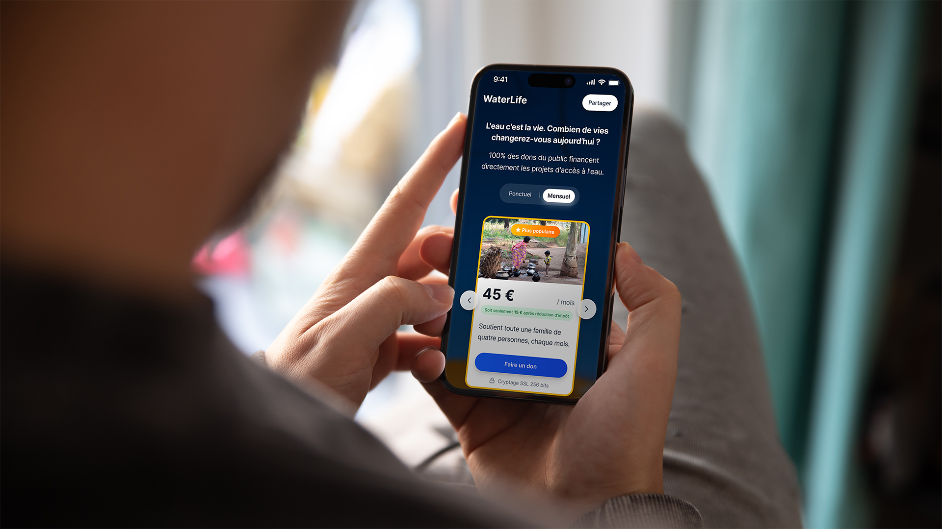 Personne tenant un téléphone, prise par dessus l'épaule